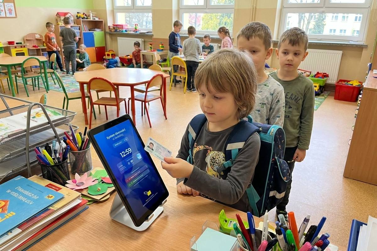 Dziecko przykłada kartę do terminala w świetlicy, w kolejce czekają kolejni uczniowie